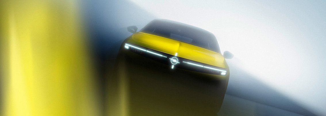 Ein gelbes Auto ist frontal und leicht von unten fotografiert. Das Fahrzeug steht in einer nebeligen, lichtdurchfluteten Umgebung. Die dominante Frontleiste mit schmalen LED-Scheinwerfern bildet eine horizontale Lichtlinie. In der Mitte befindet sich ein kreisf&ouml;rmiges Markenemblem. Die Aufnahme wirkt dynamisch und futuristisch durch starke Unsch&auml;rfen und Lichtreflexe.