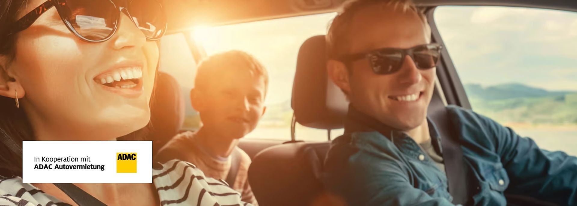 Fröhliche Familie mit Sonnenbrillen fährt Auto, sonnige Landschaft im Hintergrund; links unten ADAC-Logo mit Text „In Kooperation mit ADAC Autovermietung“.