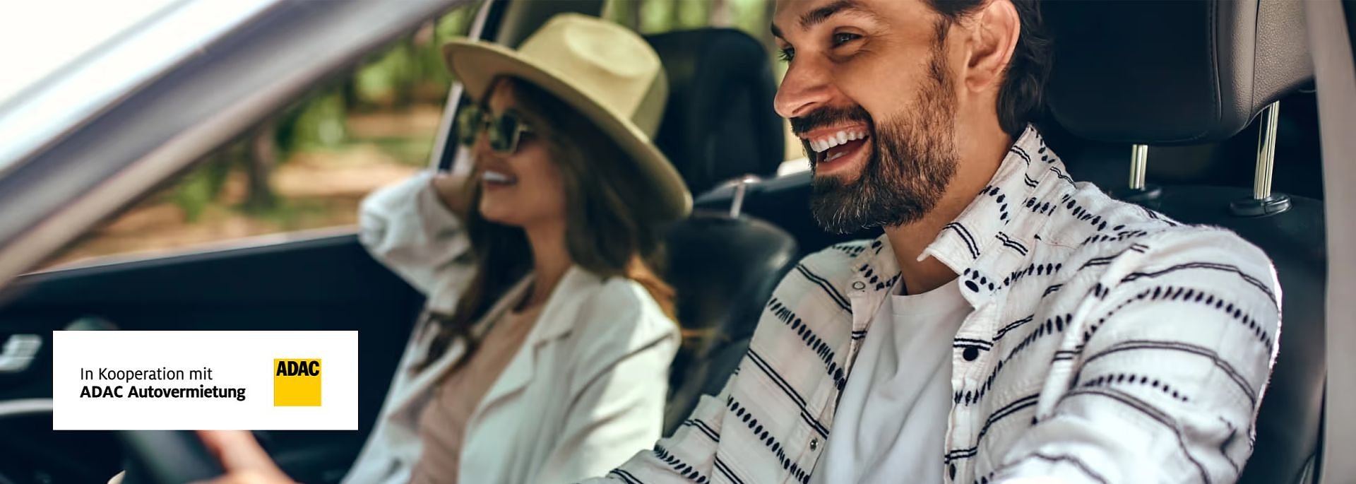 Fröhliches Paar mit Sonnenbrillen im Auto; die Frau trägt einen Hut, beide lachen. Links unten ADAC-Logo mit Text „In Kooperation mit ADAC Autovermietung“.