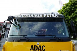 Frontansicht eines gelben ADAC-Abschleppwagens mit der Aufschrift „AUTOHAUS PETER“ über der Windschutzscheibe und dem ADAC-Logo auf der Fahrzeugfront.  (Foto: Fischer/Autohaus Peter)