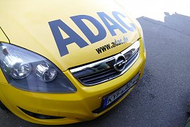 Vorderansicht eines gelben Opel-Fahrzeugs mit großem ADAC-Schriftzug auf der Motorhaube und der Webadresse www.adac.de. Das Auto steht auf Asphalt. (Foto: Fischer/Autohaus Peter)