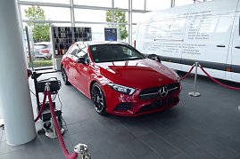 Roter Mercedes-Benz im Autohaus-Ausstellungsraum in Heiligenstadt. Das Fahrzeug ist mit roten Absperrseilen umrandet. Im Hintergrund ein großer weißer Transporter und Farbmuster. Große Fensterfronten lassen viel Tageslicht herein. (Foto: Fischer/Autohaus Peter)