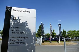 Großes weißes Mercedes-Benz Hinweisschild mit Smart-Logo, Beschriftung für Verkauf, Service, Teile/Zubehör, Gebrauchtwagen, Junge Sterne und Van ProCenter; im Hintergrund wehen mehrere Mercedes- und Smart-Flaggen, Bäume und geparkte Autos unter blauem Himmel. (Foto: Fischer/Autohaus Peter)