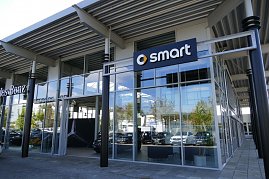 Glasfassade eines Autohauses mit Smart-Logo und Mercedes-Benz-Bereich, moderner Eingangsbereich mit großen Fenstern und metallischer Dachkonstruktion. (Foto: Fischer/Autohaus Peter)