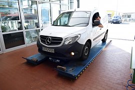 Ein weißer Mercedes-Transporter mit Fahrer am Steuer steht in der Autohaus-Werkstatt auf einem blauen Prüfstand, bereit zur Inspektion. (Foto: Fischer/Autohaus Peter)