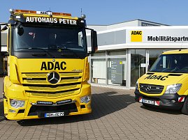 Zwei gelbe ADAC-Fahrzeuge vor dem Gebäude des ADAC Mobilitätspartners Peter in Nordhausen. Links ein großer Abschlepp-Lkw mit der Aufschrift "Autohaus Peter", rechts ein kleinerer Pannenhilfswagen. Im Hintergrund das moderne Gebäude mit Glasfront und ADAC-Logo. (Foto: Autohaus Peter GmbH)