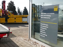  Schild an einer Glasfassade des ADAC Mobilitätspartners Peter in Nordhausen. Das Schild listet angebotene Leistungen auf, wie Pannen- und Unfallhilfe, Autovermietung, Schadenservice sowie Partnerleistungen wie Fahrzeugreparatur, Unfallreparatur, Glas- und Reifenservice, Autovermietung und Kranservice. Im Hintergrund ein gelber ADAC-Abschleppwagen. (Foto: Autohaus Peter GmbH)