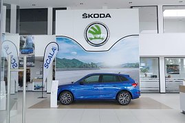 Innenansicht des koda-Autohauses mit großem weißen koda-Logo an der Wand. In der Mitte steht ein blauer koda Scala, flankiert von Werbefahnen und Postern. (Foto: Fischer/Autohaus Peter)