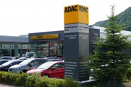 ADAC-Mobilitätspartner-Standort mit Autohaus Peter und Opel-Autohaus im Hintergrund. Vor dem Gebäude steht eine große, auffällige ADAC-Stele mit gelb-schwarzer Beschriftung und Serviceangaben. Davor parken zahlreiche Fahrzeuge. Rechts im Bild ist ein Baum. (Foto: Fischer/Autohaus Peter)
