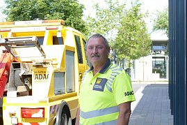 Matthias Köhler, Mitarbeiter des Autohaus Peter als ADAC Mobilitätspartner, steht in leuchtend gelber Dienstkleidung mit ADAC-Logo vor einem gelben ADAC-Pannenhilfefahrzeug. Im Hintergrund Bäume und ein moderner Gebäudeeingang. (Foto: Fischer/Autohaus Peter)