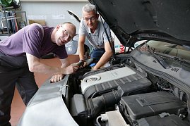 Zwei Mitarbeiter der Autowelt Peter GmbH arbeiten gemeinsam an einem VW-Motor. Einer hält ein Diagnosegerät, der andere beugt sich über den Motorraum. Beide tragen Arbeitskleidung und wirken konzentriert. (Foto: Fischer/Autohaus Peter)