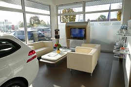 Heller Wartebereich eines Autohauses mit beigen Sesseln und Sofa, Couchtisch mit Blumen und Zeitschriften, Fernseher und großer Fensterfront. (Foto: Fischer/Autohaus Peter)