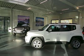 Heller Showroom mit einem weißen Jeep Renegade im Vordergrund und einem schwarzen Jeep Wrangler im Hintergrund, Poster mit Landschaftsmotiven an der Wand. (Foto: Fischer/Autohaus Peter)
