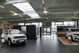 Innenraum eines modernen Jeep-Autohauses mit zwei ausgestellten weißen SUV-Modellen, großen Glasfronten und heller, offener Architektur. (Foto: Fischer/Autohaus Peter)
