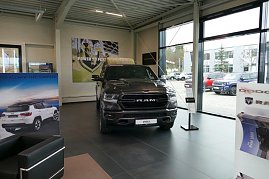 Großer schwarzer RAM-Pickup im Ausstellungsraum eines Autohauses mit großen Fenstern, daneben Werbeplakate für Jeep und Dodge. (Foto: Fischer/Autohaus Peter)