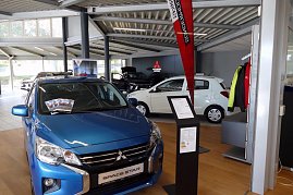 Innenansicht eines Mitsubishi-Autohauses mit mehreren ausgestellten Fahrzeugen, im Vordergrund ein blauer Space Star, im Hintergrund weitere Autos und Mitsubishi-Logo an der Wand (Foto: Fischer/Autohaus Peter)