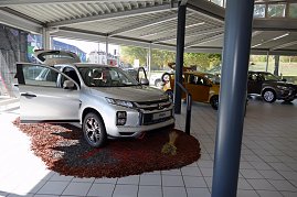 Innenansicht des Mitsubishi-Centers mit mehreren ausgestellten Autos, im Vordergrund ein silberner ASX mit geöffneter Tür auf dekorativem Untergrund, im Hintergrund weitere Fahrzeuge. (Foto: Fischer/Autohaus Peter)