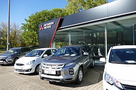 Mitsubishi-Autohaus mit großer Glasfassade, davor stehen mehrere neue Fahrzeuge in Silber, Weiß und Grau nebeneinander, links das schwarze Mitsubishi-Motors-Logo auf dem Gebäude. (Foto: Fischer/Autohaus Peter)