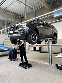 Mechaniker arbeitet unter einem angehobenen schwarzen Mercedes-Pick-up auf einer Hebebühne in der Werkstatt des Mercedes-Autohauses in Wittenberg. (Foto: Krüger / Autohaus Peter)
