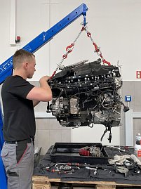 Mechaniker überprüft einen mit einem Kran angehobenen Motorblock in der Mercedes-Werkstatt. (Foto: Krüger / Autohaus Peter)