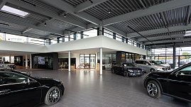 Heller Mercedes-Benz Schauraum mit mehreren ausgestellten Fahrzeugen, moderner Architektur, großen Glasfronten und industriellem Deckenstil. (Foto: Steve Dornhofer/Autohaus Peter)