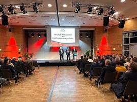 Auf einer großen Leinwand steht „Die Automobilmesse Erfurt 2025 ist eröffnet!“. Davor sprechen drei Männer (rechts Helmut Peter) auf einer Bühne, während zahlreiche Besucher im Saal zuhören. (Foto: Autohaus Peter )