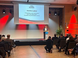 Imelda Labbé, Präsidentin des Verbandes der Internationalen Kraftfahrzeughersteller (VDIK), spricht am Rednerpult. Ihr Name und Titel sind groß auf der Leinwand zu sehen. (Foto: Autohaus Peter )
