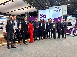 Eine große Gruppe von Männern und einer Frau posiert gemeinsam für ein Foto vor einem Stand der Firma TEAG Mobil auf der Automobilmesse Erfurt 2025. Im Hintergrund sind ein Elektroauto, ein Ladegerät und Werbebanner zu sehen. (Foto: Autohaus Peter )