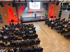 Blick von oben auf die Bühne: Prof. Dr. Mario Voigt hält eine Rede, sein Name steht groß auf der Leinwand. (Foto: Autohaus Peter )