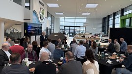 Ein Referent hält einen Vortrag mit der Präsentation „Herausforderungen der Energiewende“. Teilnehmende sitzen an runden Tischen mit Kaffee und Frühstücksplatten. (Foto: Autohaus Peter)