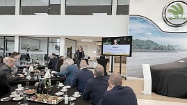 Eine Rednerin steht im koda-Ausstellungsraum vor einem Bildschirm mit der Folie „Fragen? Vielen Dank für Ihre Aufmerksamkeit!“. Gäste sitzen an gedeckten Frühstückstischen und hören zu. (Foto: Autohaus Peter)