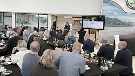 Mehrere Dutzend Gäste sitzen an langen Tischen und schauen auf die Rednerin. Auf dem Bildschirm ist die Abschlussfolie „Fragen?“ zu sehen. Im Vordergrund Teller und Getränke. (Foto: Autohaus Peter)
