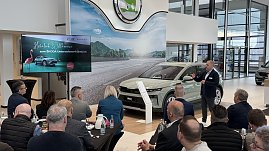 Ein Referent spricht vor einem Publikum, während der neue koda Elroq im Showroom präsentiert wird. Links auf einem Bildschirm die Begrüßungsfolie „Herzlich Willkommen zum KODA Unternehmerfrühstück“. (Foto: Autohaus Peter)