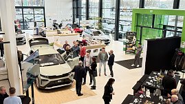 Im hellen Ausstellungsraum des koda Autohauses steht ein neuer koda Elroq mit geöffneten Türen und Kofferraum. Mehrere Gäste betrachten das Fahrzeug, einige unterhalten sich in kleinen Gruppen. Im Hintergrund sind weitere Autos sowie der Empfangsbereich mit der Beschilderung „Information“ und „Kasse“ zu sehen. Rechts am Rand ein Buffetbereich mit leeren Tassen und Tellern, daneben ein schwarzer Fotohintergrund. (Foto: Autohaus Peter)