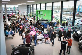 Blick von oben in den hellen Ausstellungsraum des Autohauses. Viele Besucher schauen sich an langen Tischen bunte Schulranzen an. Im Hintergrund stehen Autos, rosa Flamingos als Deko hängen von der Decke. (Foto: Autohaus Peter)