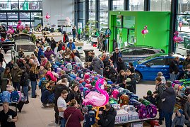 Großer Ausstellungsraum im koda Autohaus, gefüllt mit vielen Menschen. In der Mitte sind lange Tische voller bunter Schulranzen. Mehrere koda-Fahrzeuge stehen zwischen den Besuchern. Rosa Flamingo-Dekorationen hängen im Raum. (Foto: Autohaus Peter)