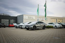 Mehrere koda-Fahrzeuge stehen vor dem Gebäude „koda Plus Autowelt Peter“. Zwei grüne Fahnen wehen im Vordergrund. Links im Bild parken weitere Autos. (Foto: Autohaus Peter)