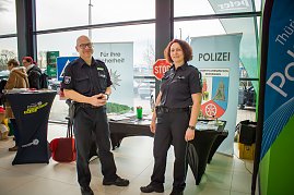 Zwei Polizisten in Uniform stehen vor einem Infostand der Landespolizeiinspektion Nordhausen. Hinter ihnen Banner mit Polizeiwappen, Infomaterial und einem Stoppschild. (Foto: Autohaus Peter)