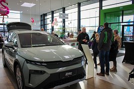 Ein neues koda-Fahrzeug mit geöffnetem Kofferraum steht im hellen Showroom. Besucher unterhalten sich daneben, rosa Flamingo-Dekorationen hängen von der Decke. (Foto: Autohaus Peter)