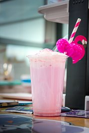 Ein rosa Milchshake oder Cocktail in einem Plastikbecher mit Sahnehaube. Am Strohhalm ist eine pinke Flamingo-Deko befestigt. (Foto: Autohaus Peter)