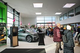Großer Ausstellungsraum mit neuen koda-Fahrzeugen. Viele Menschen gehen durch die Halle. Rosa Flamingos sind als Dekoration aufgestellt. (Foto: Autohaus Peter)