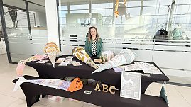 Eine Frau sitzt hinter einem Stand im Autohaus. Auf den Tischen liegen farbenfrohe, große Schultüten und Informationsmaterialien. Vorne große Buchstaben „ABC“. (Foto: Autohaus Peter)