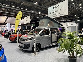 Grauer Opel Crosscamp mit geöffnetem Hochdach und Schiebetür, präsentiert auf der Messe. Daneben Besucher und weitere Opel-Fahrzeuge. (Foto: Autohaus Peter Gruppe)
