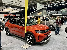 Ein roter Opel SUV im Vordergrund, dahinter ein Opel Crosscamp Camper mit geöffnetem Hochdach. Besucher stehen daneben. (Foto: Autohaus Peter Gruppe)