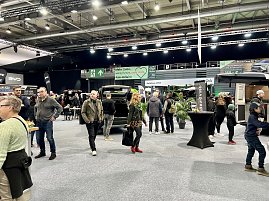 Besucher gehen zwischen verschiedenen Ständen hindurch. Sicht auf SUVs und Camper, mit schwarzen und grünen Messebannern im Hintergrund. (Foto: Autohaus Peter Gruppe)