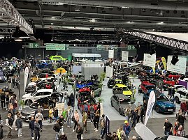 Panoramaaufnahme der Messehalle mit zahlreichen Autos in verschiedenen Farben, vielen Besuchern und großen Markenbannern. (Foto: Autohaus Peter Gruppe)