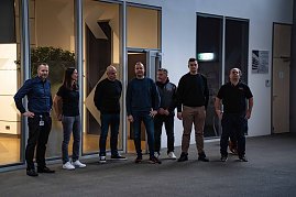 Acht Personen stehen zusammen in einer Halle, im Hintergrund Glasfronten und Türen. (Foto: Daimler Truck AG)
