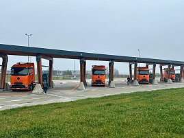 Vier eActros 600 Lkw der Firma Schade parken nebeneinander unter einem überdachten Ladepark. Ein Fahrer steht jeweils bei den Fahrzeugen. (Foto: Autohaus Peter)