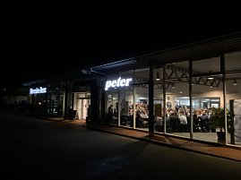 Das Autohaus Peter in Duderstadt bei Nacht. Durch die Fenster ist der volle Saal mit zahlreichen Gästen sichtbar. (Foto: Autohaus Peter)