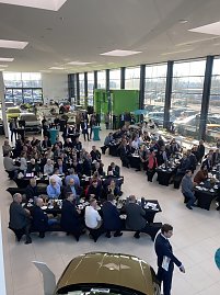 Weitwinkelaufnahme der Skoda Autowelt Peter mit vielen Sitzgruppen, an denen Gäste frühstücken. Rechts und links stehen Autos, hinten große Fensterfront mit Tageslicht. (Foto: Autohaus Peter)